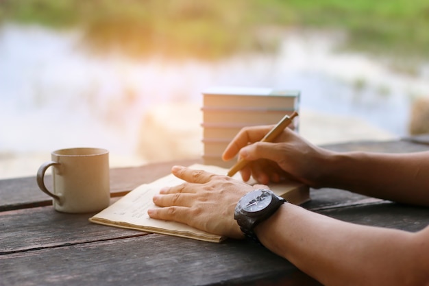 Mannelijke hand die sommige gegevens in notitieboekje op het bureau schrijven