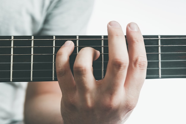 Foto mannelijke hand met een barré-akkoord op de akoestische gitaar, close-up.