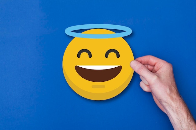 Mannelijke hand met een emoji emoticon engel smiley hoofd icoon