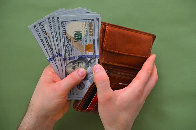 mannelijke hand met een portemonnee en geld op een groene achtergrond