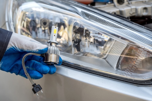 Mannelijke hand met gloeilamp van autokoplamp voor reparatie auto, close-up