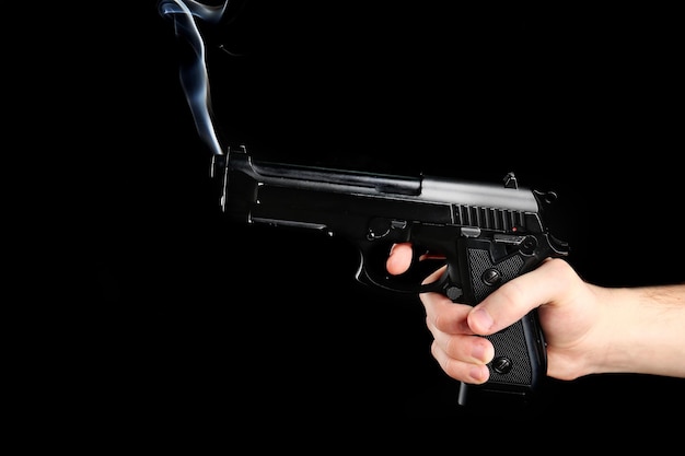 Foto mannelijke hand met rokend pistool op zwarte achtergrond