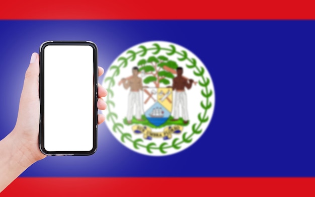 Mannelijke hand met smartphone met blanco scherm op de achtergrond van wazige vlag van Belize Close-upweergave