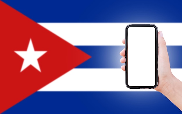 Mannelijke hand met smartphone met blanco scherm op de achtergrond van wazige vlag van Cuba Close-upweergave