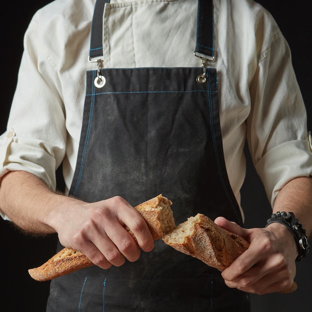 Mannelijke handen breken vers gebakken brood, close-up