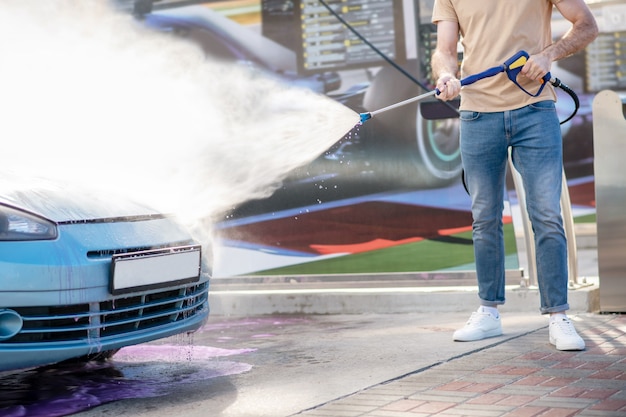 Mannelijke handen die auto water geven met water uit de slang