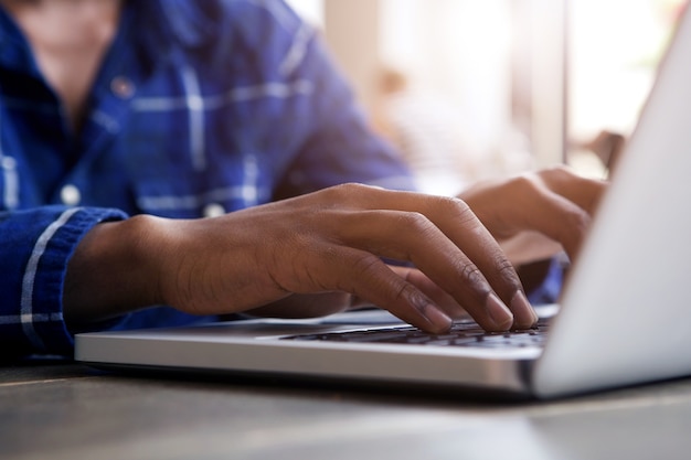 Mannelijke handen die op laptop computer typen