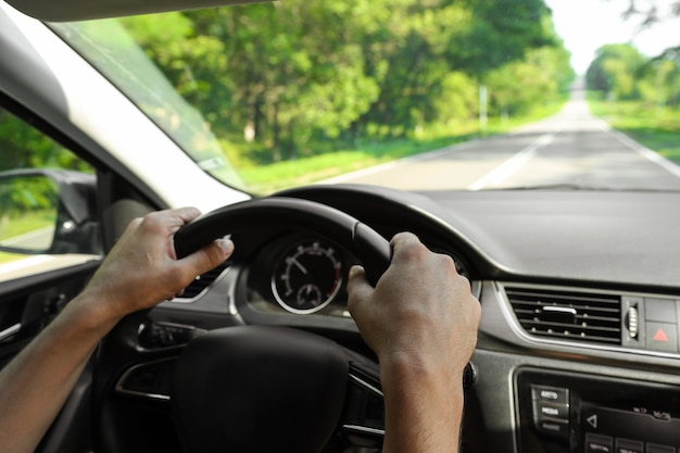 Mannelijke handen houden het stuur van een auto vast terwijl ze naar binnen rijden