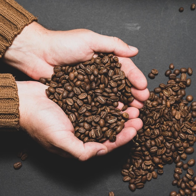 Mannelijke handen houden koffie op een donkere achtergrond