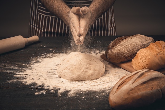 Mannelijke handen kneden het deeg. Chef-kok die brood en broodje kookt