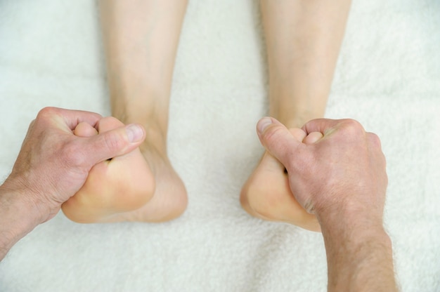 Mannelijke handen masseren voeten.