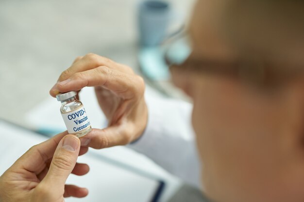 Mannelijke handen met fles covid-vaccin