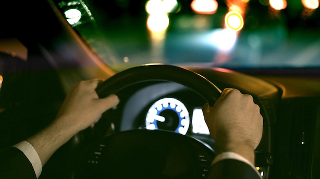 Foto mannelijke handen op de achterbank van het stuur, geschoten met zicht op de weg 's nachts