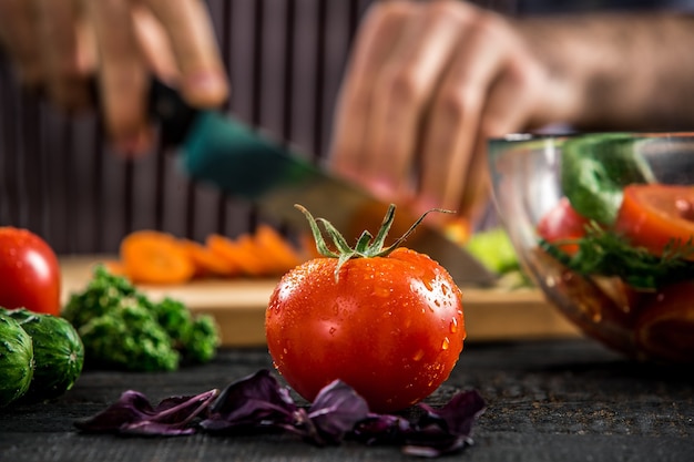 Mannelijke handen snijden groenten voor salade