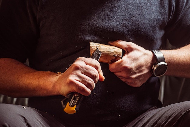 Mannelijke handen snijden hout met een mes