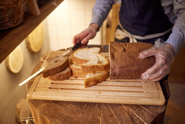 Mannelijke handen snijden tarwebrood op de houten plank, selectieve aandacht.