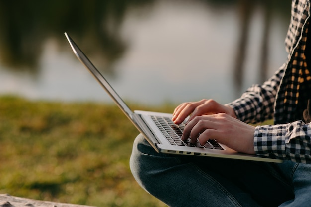 Mannelijke handen typen op laptop in het park