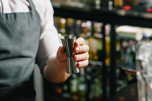 Mannelijke handen van de barman, maakt een cocktail op de bar, glazen met ijs.