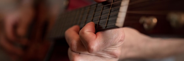 Mannelijke handen van een oudere senior blanke man die een klassieke gitaar vasthoudt en speelt close-up thuis onprofessionele gezichtsloze gitarist mensen spelen amateurmuziek binnenlandse hobby's en vrije tijd banner