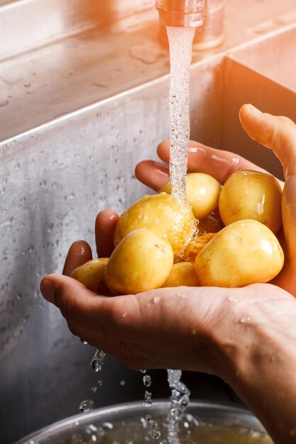 Mannelijke handen wassen aardappelen.