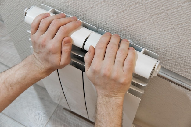 Mannelijke handen wat betreft witte huisverwarmingsradiator Moderne huisverwarmingstechnologie