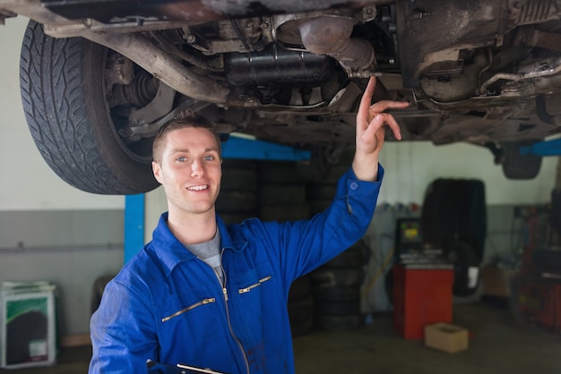 Mannelijke hersteller die onder auto onderzoekt