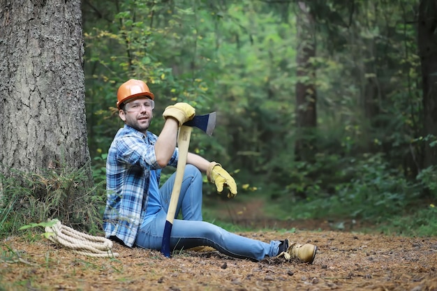 Mannelijke houthakker in het bos. een professionele houthakker inspecteert bomen op kap.