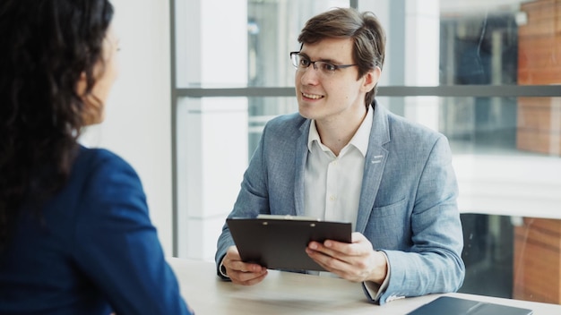 Mannelijke HR-manager die vrouwelijke kandidaat de hand schudt na een sollicitatiegesprek in een modern kantoor