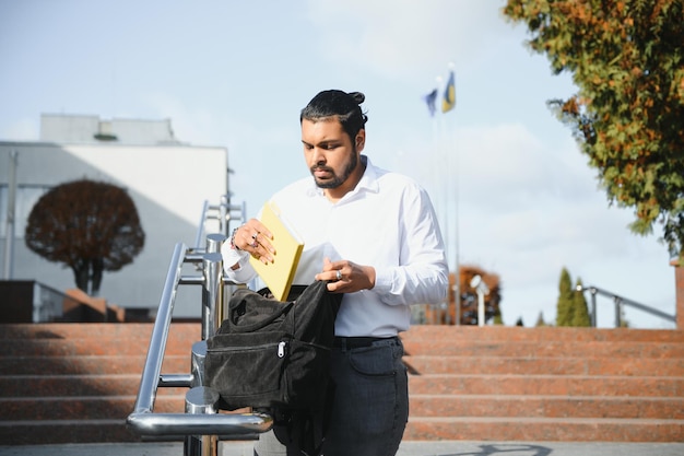 Mannelijke Indiase student die aan de universiteit staat met boek