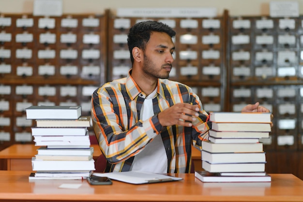 Mannelijke Indische student bij de bibliotheek met boek