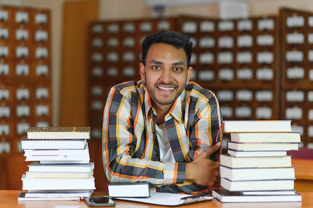 Mannelijke Indische student bij de bibliotheek met boek