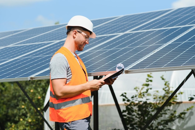 Mannelijke ingenieur in beschermende helm die fotovoltaïsch zonnepaneelsysteem installeert Ecologisch concept voor alternatieve energie