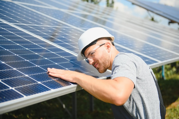 Mannelijke ingenieur in beschermende helm die fotovoltaïsch zonnepaneelsysteem installeert Ecologisch concept voor alternatieve energie