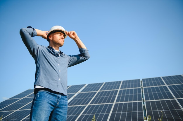 Mannelijke ingenieur in een helm die in de buurt van de zonnepanelen staat en omhoog kijkt Groene ecologische energieopwekking Zonnestation ontwikkelingsconcept Woningbouw
