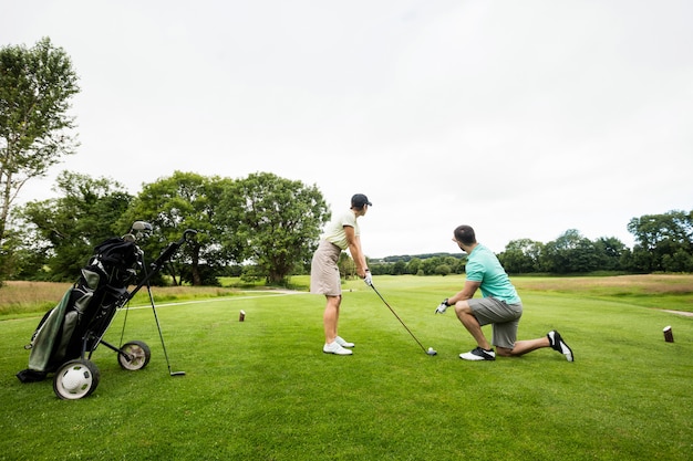 Mannelijke instructeur bijwonende vrouw in het leren van golf