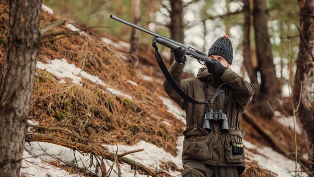 Mannelijke jager klaar om te jagen met pistool en wandelen in het bos