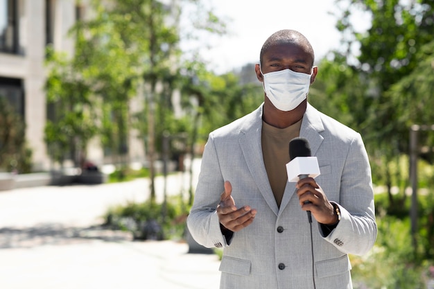 Mannelijke journalist die een medisch masker draagt
