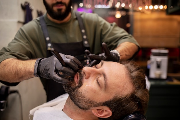 Mannelijke kapper die de baard van zijn cliënt trimt