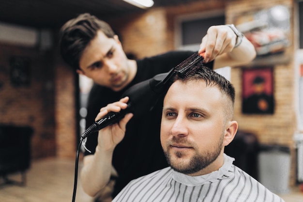 Mannelijke kapper die haar van hipster droogt