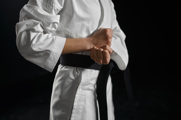 Mannelijke karatevechter in witte kimono met zwarte band, gevechtshouding. Karateka op training, vechtsporten, training voor vechtwedstrijden