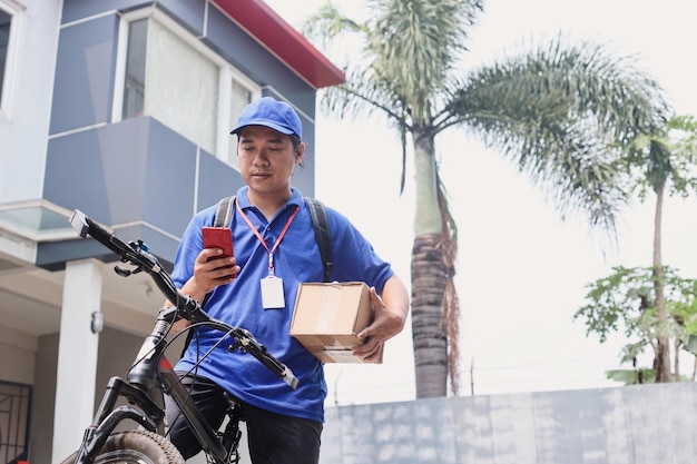 mannelijke koerier die smartphone gebruikt om adres te vinden en werkrapport van verzendingsstatus te verzenden