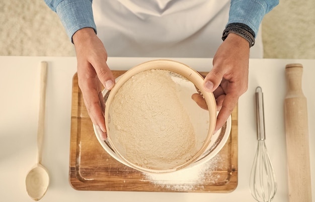 Mannelijke kok die voedsel in de huiskeuken bereidt om deeg te maken