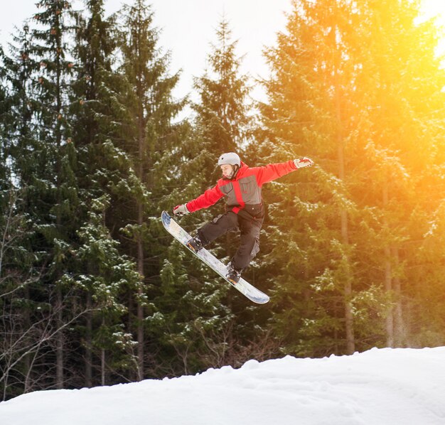 Mannelijke kostganger springen en houdt een hand op de snowboard