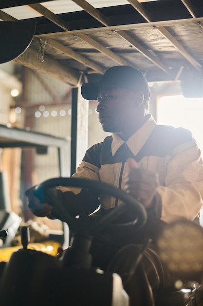 Mannelijke magazijnmedewerker die op vorkheftruck werkt