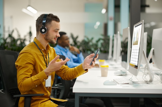 Mannelijke manager in koptelefoon op zijn werkplek, idee ontwikkelen in it-kantoor. professionele werknemer, planning of brainstormen. succesvolle zakenman werkt in modern bedrijf