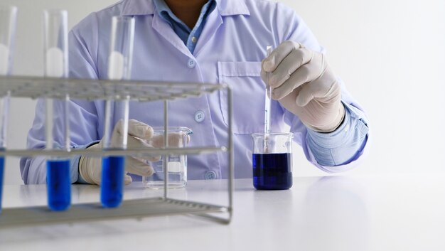 Mannelijke medische of wetenschappelijke laboratorium onderzoeker voert tests uit met blauwe vloeistof in het laboratorium. Laboratorium apparatuur en wetenschappelijke experimenten concept.