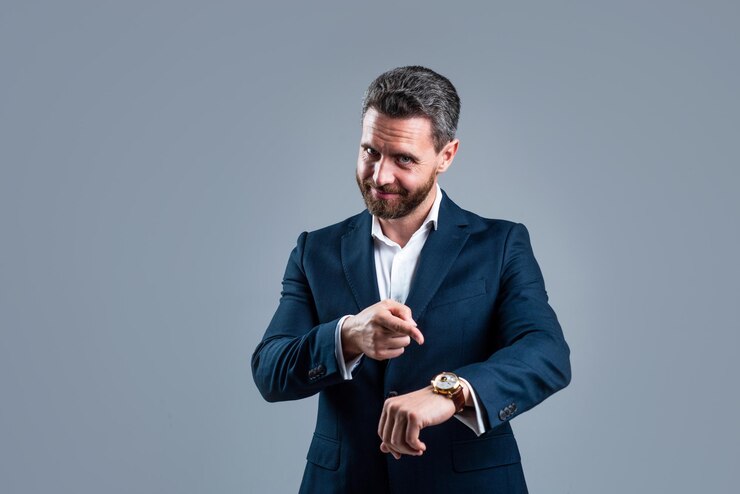 Mannelijke mode accessoire man in jas op grijze achtergrond zelfverzekerde zakenman met handhorloge meer tijd nodig modern leven en zakelijk succes ceo of baas dragen formele kleding