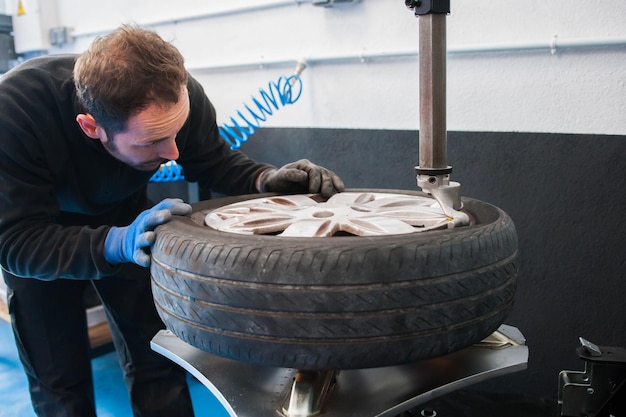 Foto mannelijke monteur die een band vasthoudt in een autowerkplaats