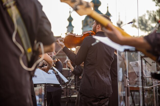 Mannelijke muzikant viool spelen in orkest buitenshuis