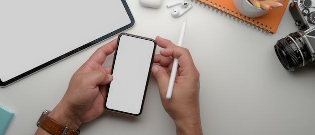 Mannelijke ondernemer die smartphone boven wit bureau met laptop en levering gebruiken